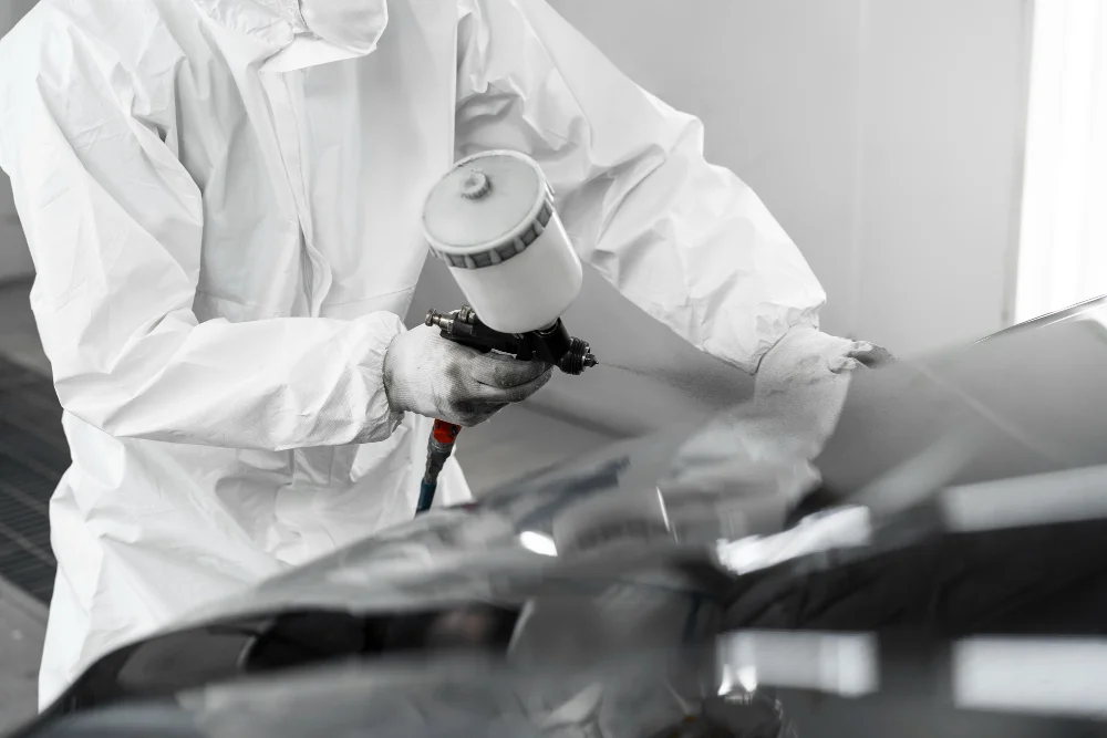 Worker painting car and wearing protective suit